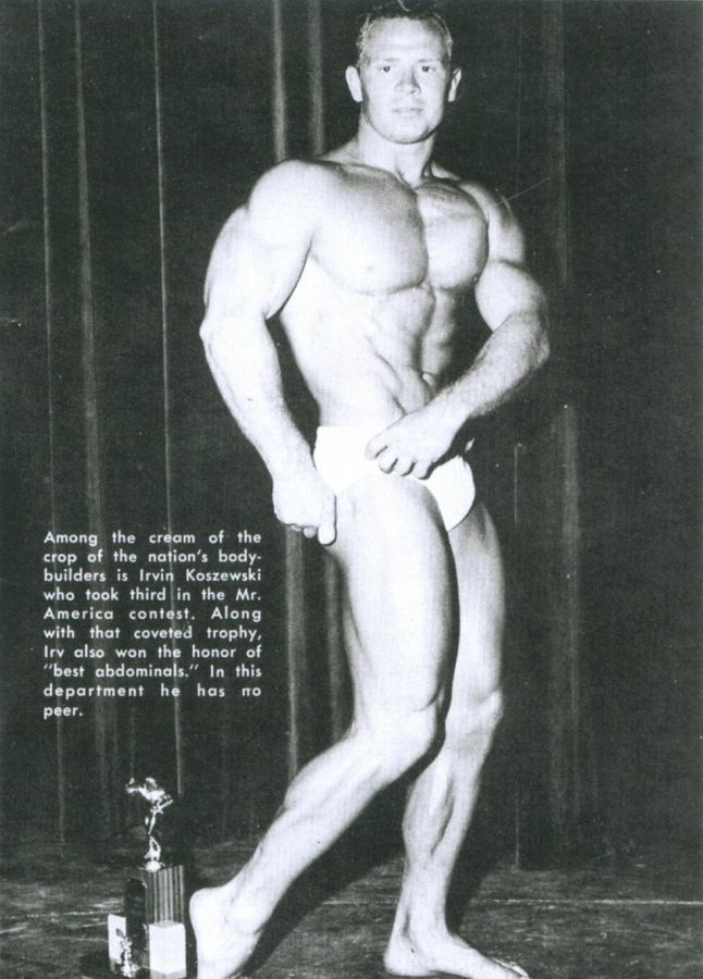 Magazine page with a black and white photograph of a muscular bodybuilder in posing trunks standing on a stage next to a trophy
