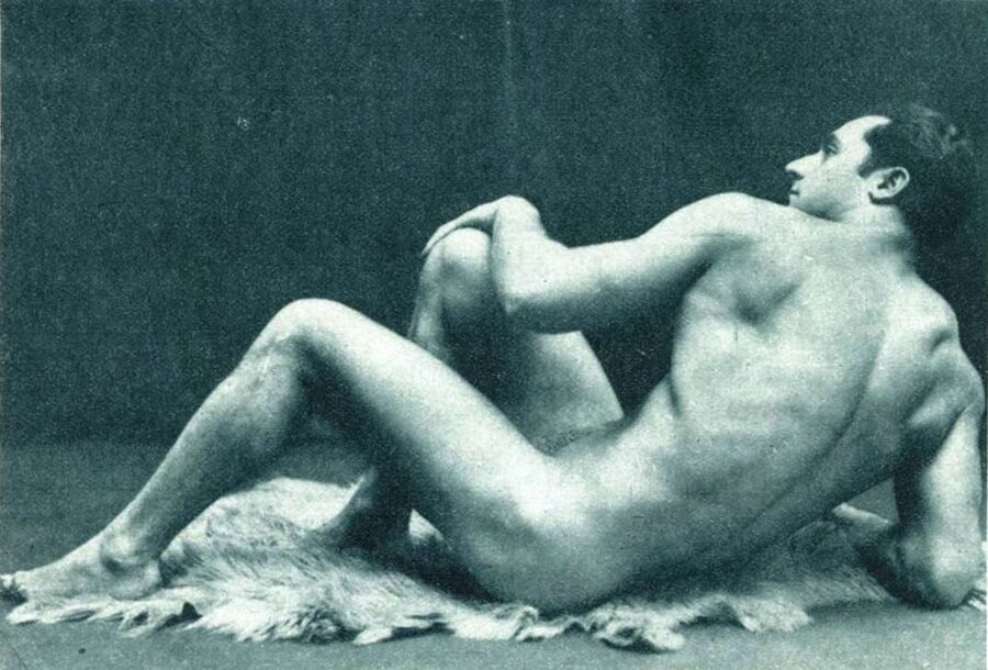 Photograph of the bodybuilder Charles Atlas lying naked on a fur rug, propped on one elbow with a knee drawn up