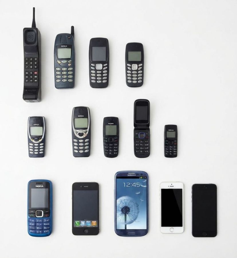 Row of mobile phones from a large 1990s handset with an aerial to modern touchscreen smartphones