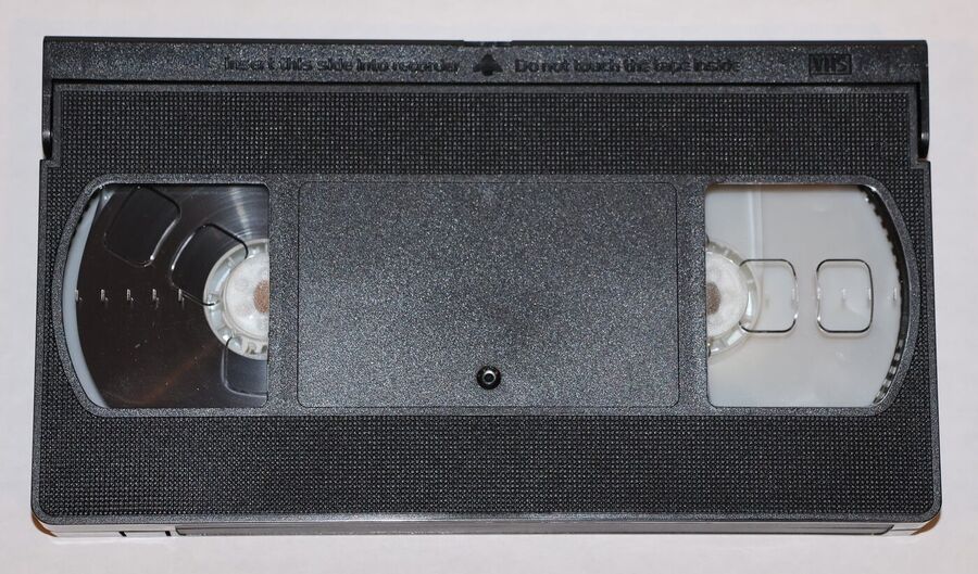A black VHS videocassette seen from the front, with two transparent windows showing the tape reels