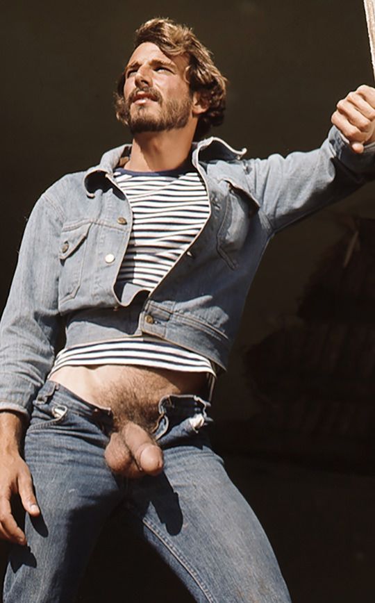 Al Parker in a denim jacket and striped T-shirt, his jeans open, holding on to a beam above his head