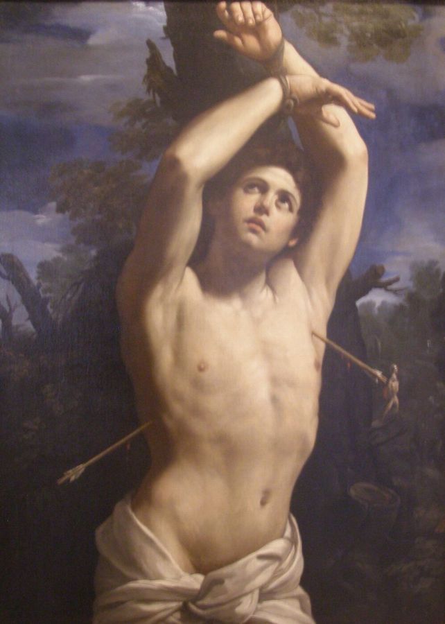 A muscular, nearly naked man with his arms tied above his head to a tree, two arrows in his body, a white cloth around his hips, looking up